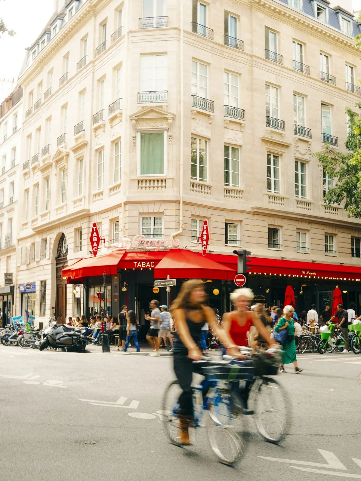 Deux cyclistes passent devant un café parisien