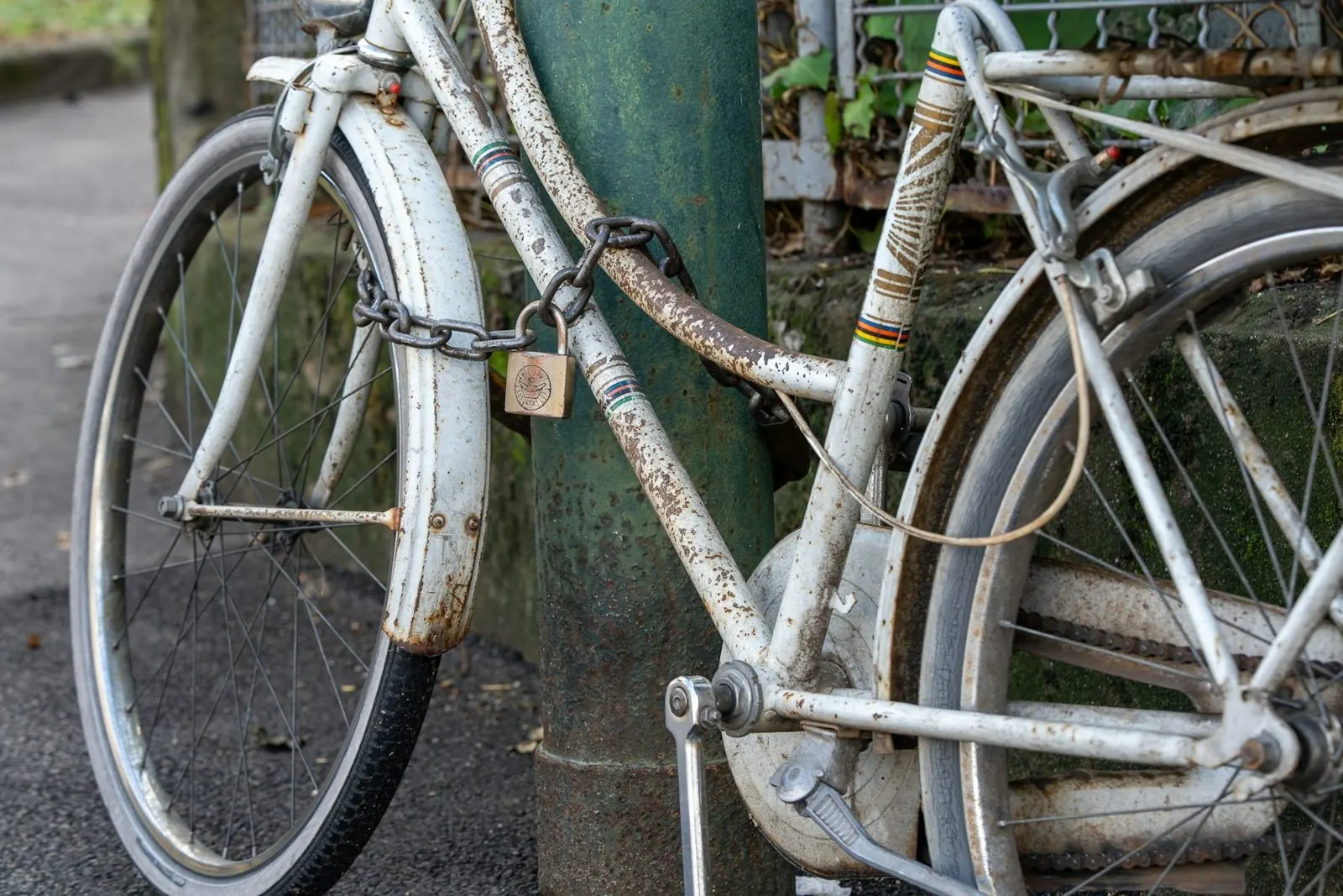 Vieux vélo blanc attaché à un poteau